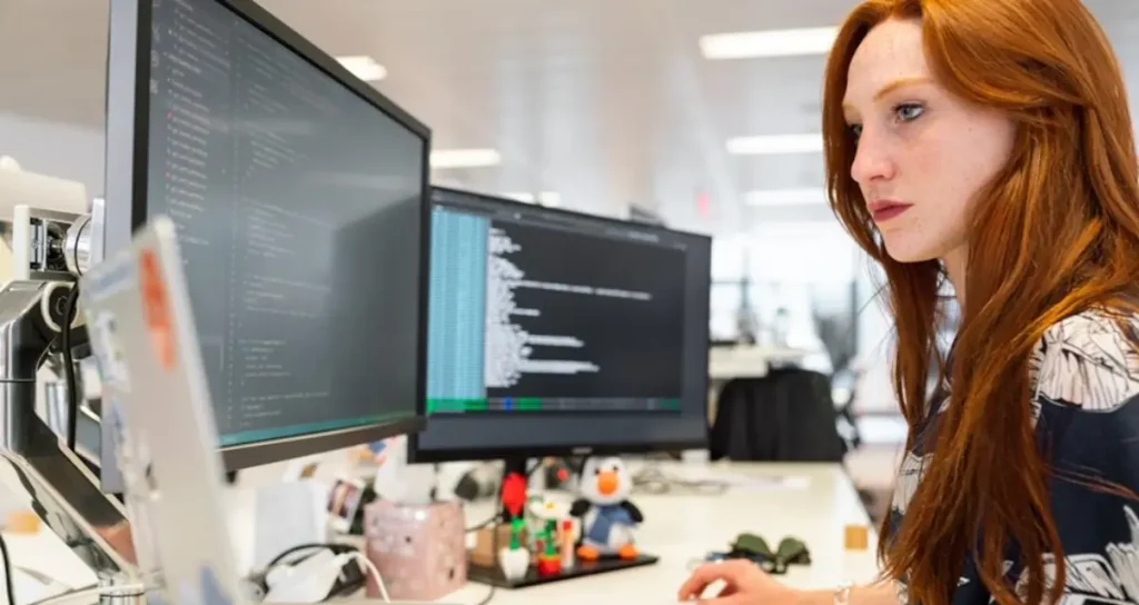 A woman in an office researching customer journey orchestration platforms on her computer